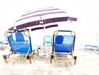 Deck chairs on beach against sky