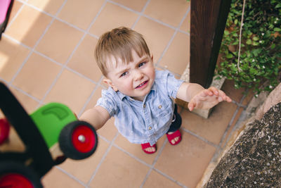 High angle view of cute boy crying while standing on tiled floor