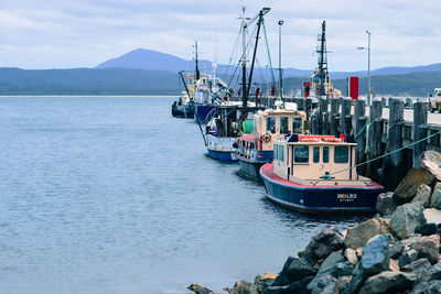 Fishing boats moored by pier at lake