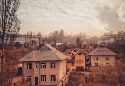 Houses in city against sky during sunset