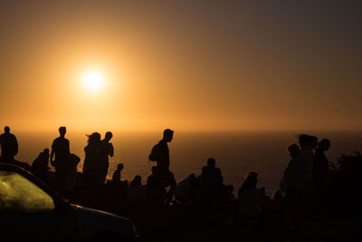 Silhouette people by sea against sky during sunset