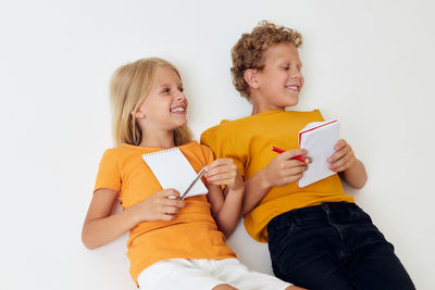 Smiling kids holding notebook against white background