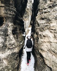 Rear view of woman walking amidst rock formation