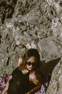 High angle view of woman wearing sunglasses sitting on rock formation