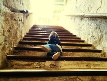 Rear view of woman sitting on staircase