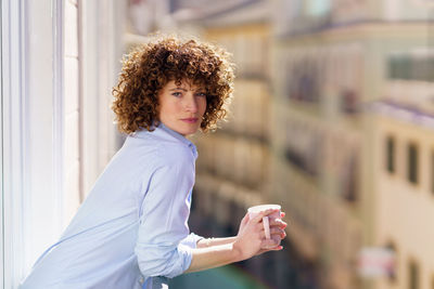 Portrait of young woman standing against building