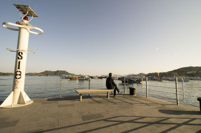 Woman by sea against clear sky