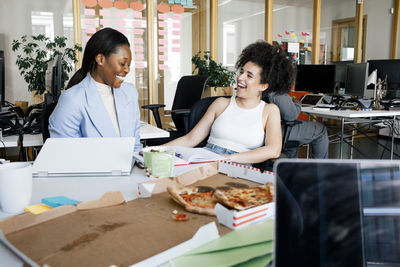 Happy businesswomen laughing while sitting at office