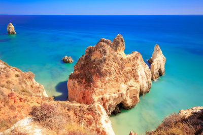 Rock formation on beach against sky