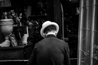 Rear view of man in hat sitting outdoors