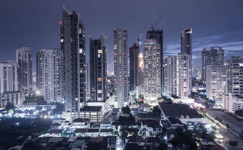 Illuminated buildings in city against sky at night