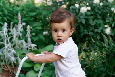 Portrait of cute baby boy standing against plants