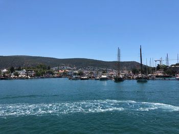 Scenic view of sea by buildings against clear blue sky