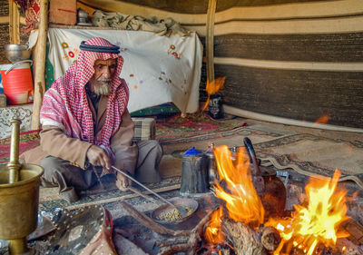Man wearing traditional clothing cooking food in tent