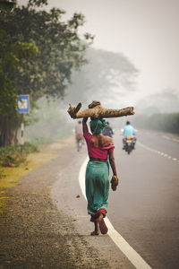 Rear view of woman walking on road