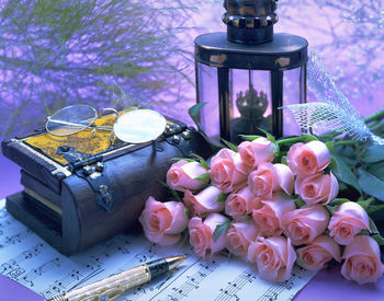 Roses and sheet music by lantern on table