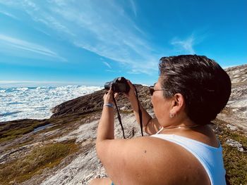 Side view of woman looking at sea against sky