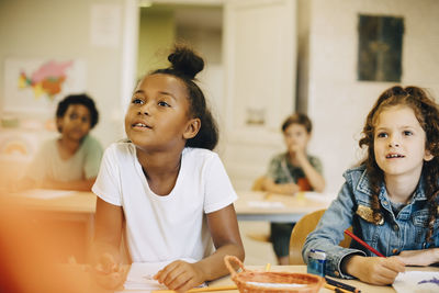 Girls learning at desk while sitting in classroom