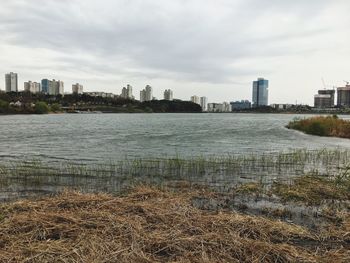 City skyline by river against sky