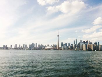 City at waterfront against cloudy sky