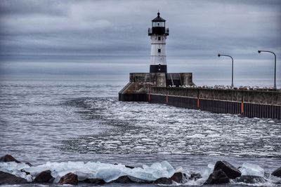 Lighthouse on beach against sky