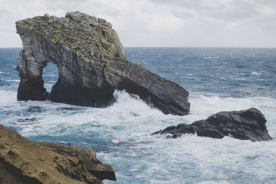 Rock formation in sea against sky
