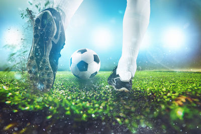 Low section of woman playing soccer ball on grass