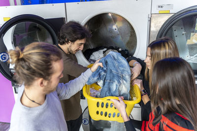 High angle view of friends putting clothes in washing machine