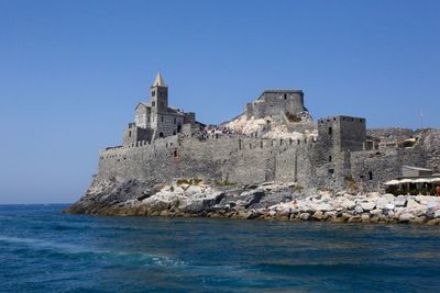 Castle by sea against clear blue sky