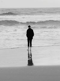 Rear view of girl standing on shore at beach