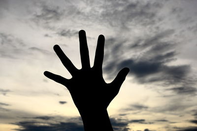 Cropped hand of person gesturing against sky