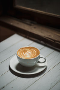 Latte art coffee on wooden table in coffee shop