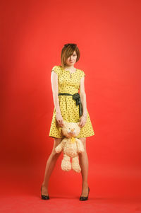 Portrait of young woman standing against red background