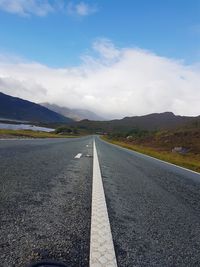 Road by mountains against sky