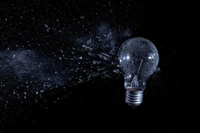 Close-up of illuminated light bulb against black background