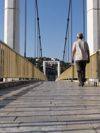 Rear view of man on railing in city against clear sky