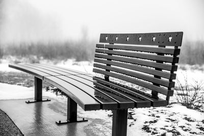 Empty bench in park during winter