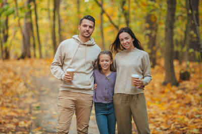 Full length portrait of a young woman with autumn tree