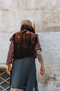 Rear view of woman standing against wall in city