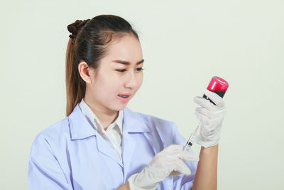 Close-up doctor with syringe and medicine bottle over gray background