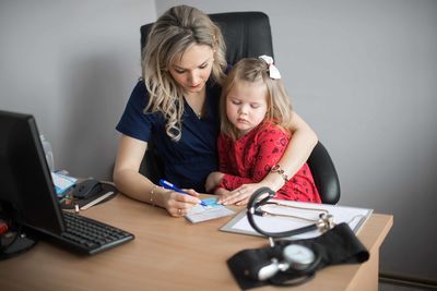 Mother and daughter sitting on table