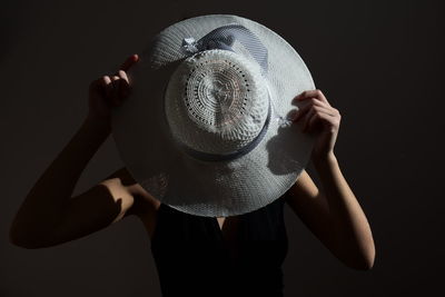 Digital composite image of woman holding hat against black background