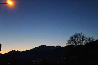 Scenic view of silhouette mountains against clear blue sky at sunset