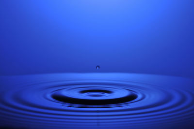 Close-up of drop falling on blue water