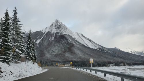 Road by snow covered mountain against sky