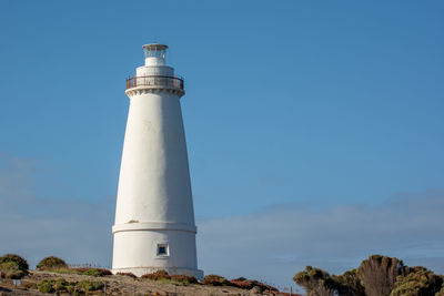 Low angle view of lighthouse by building against sky