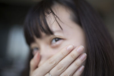 Close-up portrait of young woman covering mouth