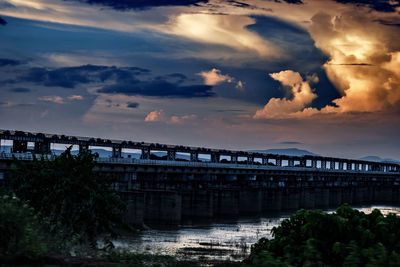 Bridge over river against cloudy sky