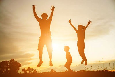 Low angle view of silhouette people jumping against sky during sunset