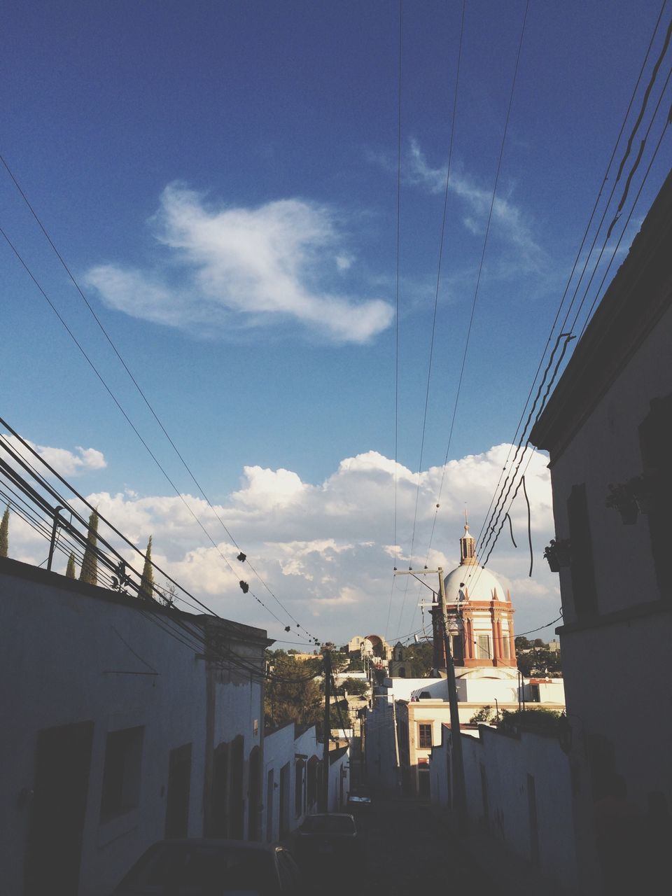 building exterior, architecture, built structure, sky, power line, low angle view, cloud - sky, city, blue, transportation, residential structure, cloud, building, electricity pylon, residential building, cable, house, outdoors, day, sunlight